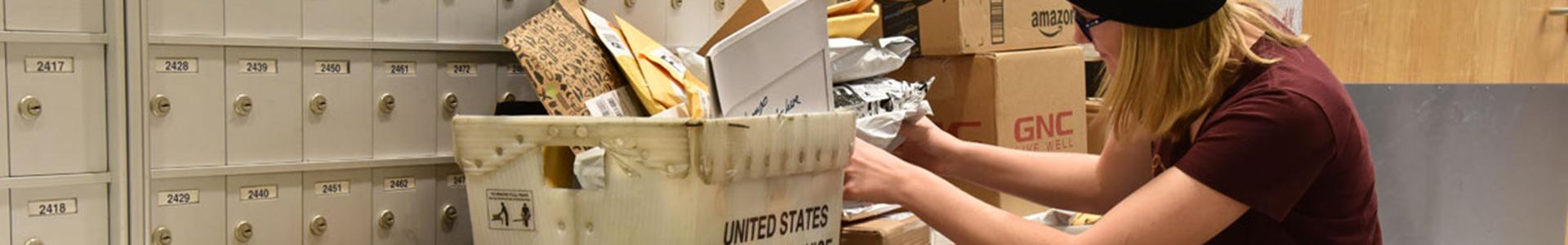 Student worker going through packages and US Mail in the UMN Crookston Post Office