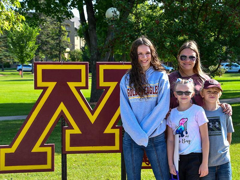 Female student and her family members standing next to the Big block M during Welcome Weekend 2023