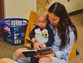 Early Childhood Development Center student staff reading a book to a child.
